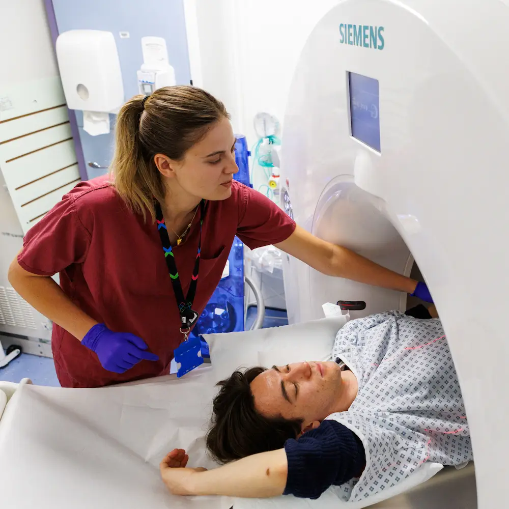 A radiographer scanning a patient using the MRI scanner in the imaging department of West Middlesex University Hospital, London
