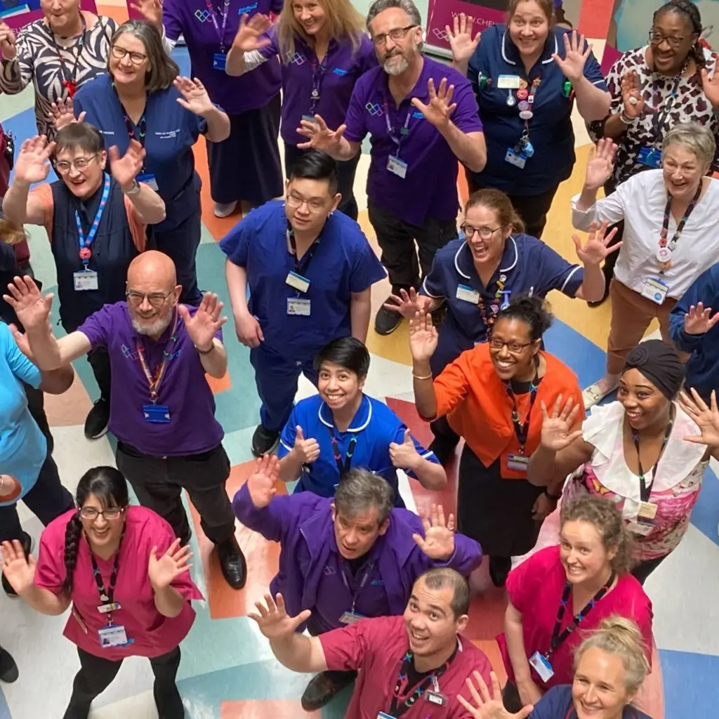 A group of healthcare professionals waving and smiling at the camera