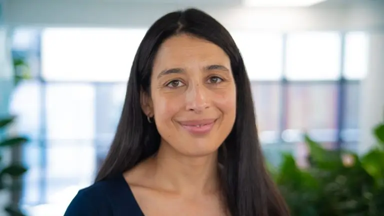 Woman with long, straight, dark hair smiling at the camera