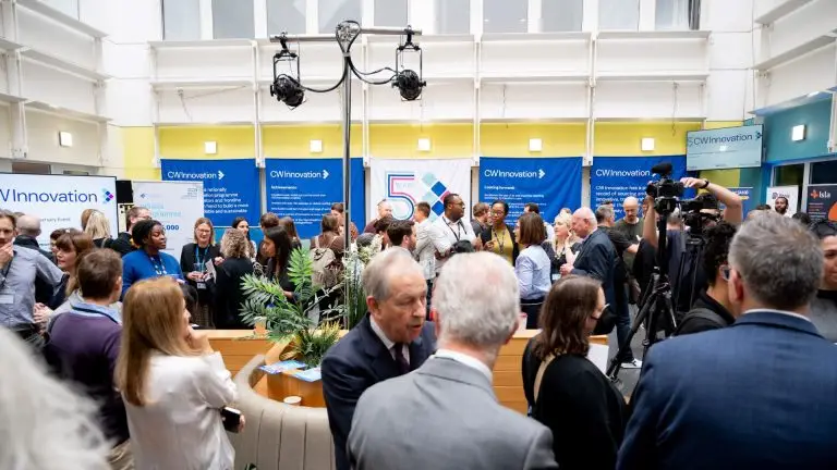 Lots of people chatting and networking at an event, with banners saying CW Innovation hanging on one wall