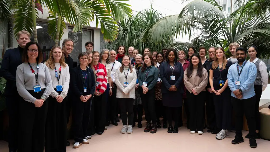 Lots of people standing in an indoor garden posing for a team photo