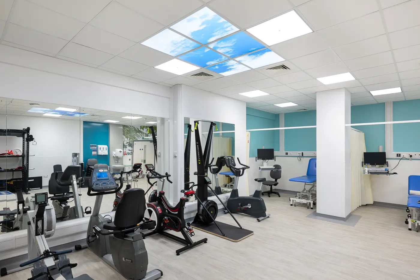 Gym with equipment and LED ceiling tiles depicting blue sky and clouds