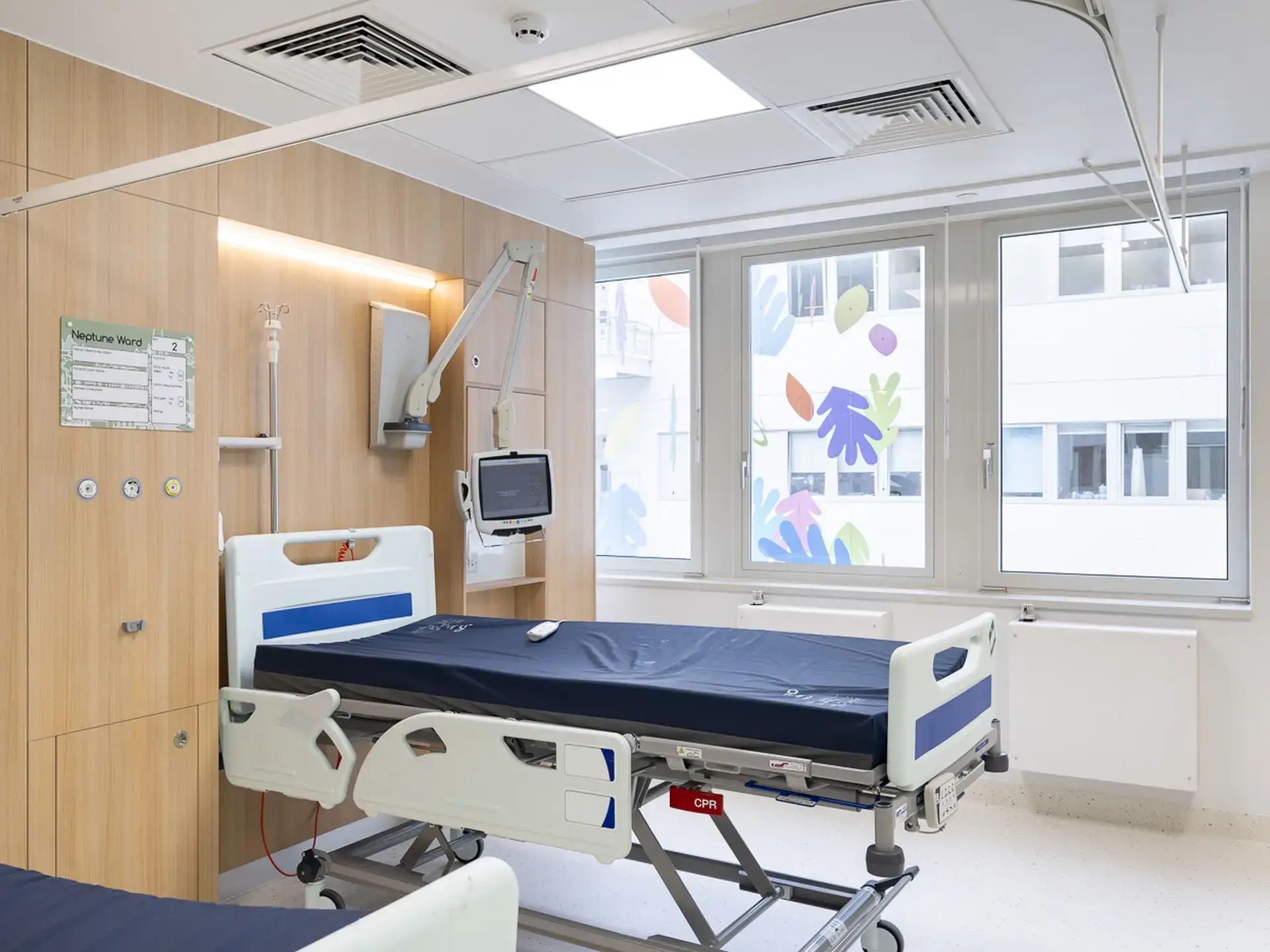 Hospital room with a bed, oak finish wall, large windows