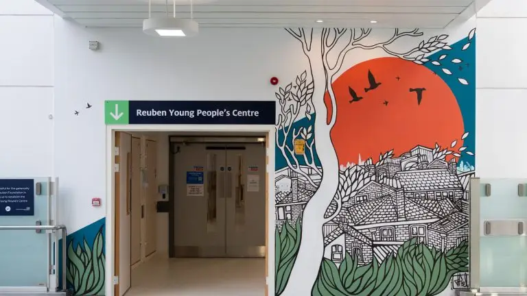 Entrance to the Reuben Young People's Centre, with a colourful mural on the wall and a sign above the double doors
