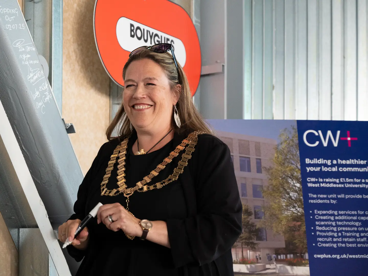 Amy Croft, Mayor of Hounslow, wearing her chains of office, holding a pen to sign the steel at the topping-out ceremony at West Mid