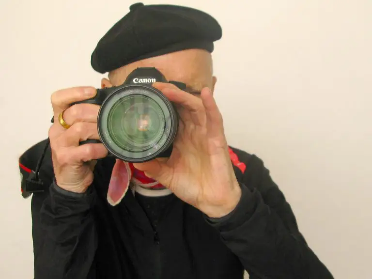 Man wearing a black beret and black top, with a camera held up to his face (man is Richard Duebel, a patient who shared his enjoyment of the art collection)