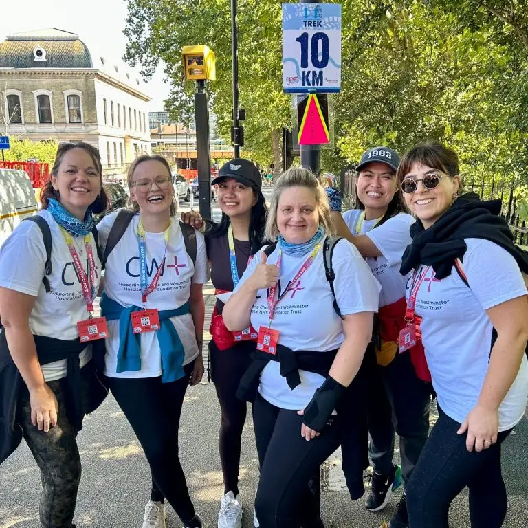 Six women wearing CW+ t-shirts standing under a '10km' sign
