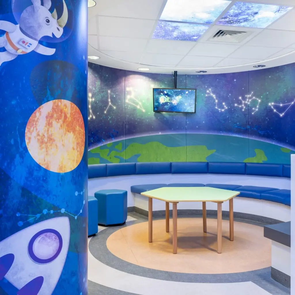 Saturn ward at Chelsea and Westminster Hospital - the image shows a seating area with a space theme. The walls have constellations, the curve of the earth, planets and rockets painted on them